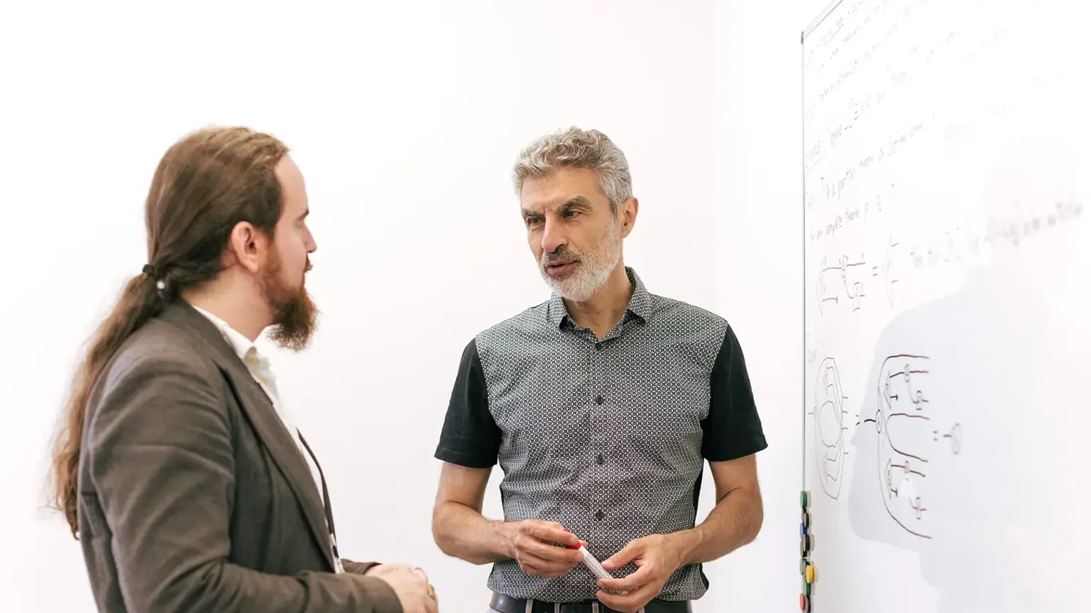 A photo of Yoshua Bengio and Davidad Dalrymple standing in front of a white board